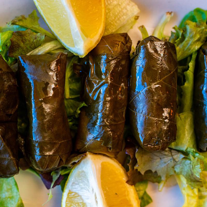 Grape leaves stuffed with rice and spices, served over lettuce leaves with lemon wedges